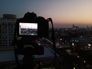 Woman photographing cityscape at sunset