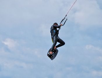 Low angle view of man kiteboarding against sky