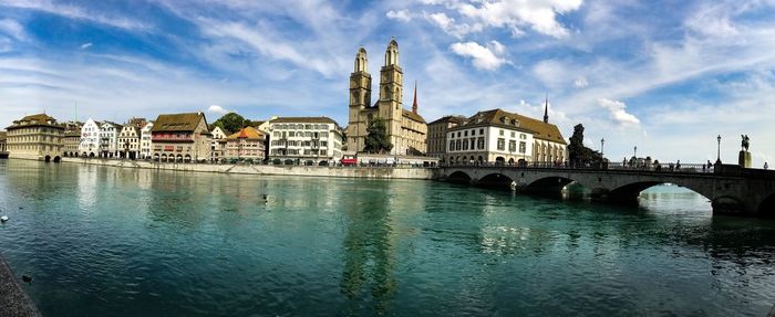 View of buildings at waterfront against cloudy sky