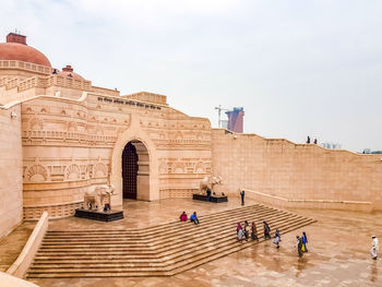 People at historical building against sky