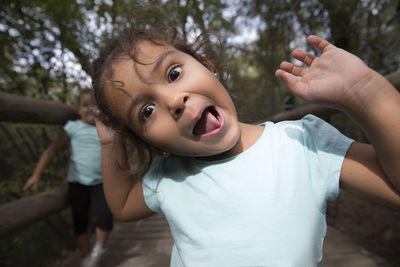 Portrait of cute girl making face while standing on footbridge