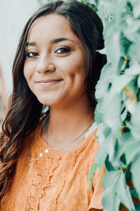 Portrait of smiling woman by plants outdoors