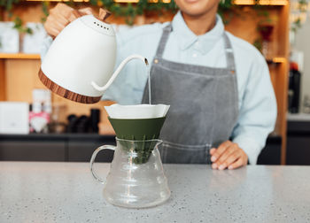 Midsection of woman holding drink on table