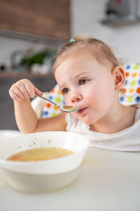 Cute girl eating food while sitting at home