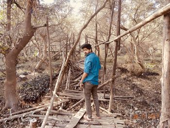 Full length of boy standing by tree in forest