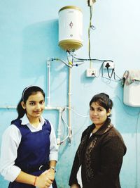 Portrait of smiling friends standing against wall