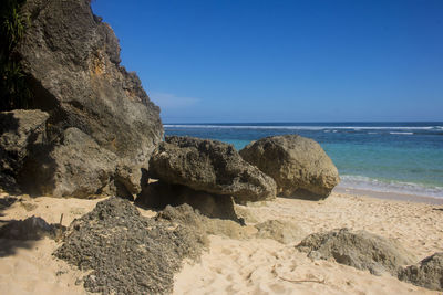 Rocks on beach against clear blue sky