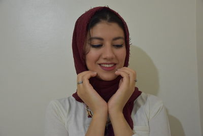 Portrait of smiling young woman against wall