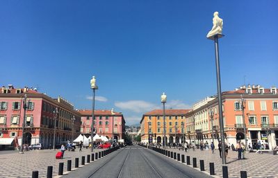 Street lights in city against clear blue sky