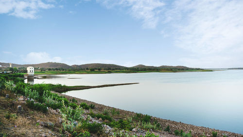 Scenic view of lake against sky surrounded by greenery