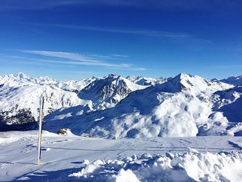 Scenic view of snowcapped mountains against blue sky