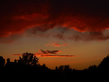 Low angle view of silhouette trees against dramatic sky