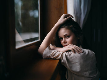 Side view of woman looking through window