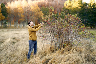 Full length of man photographing while standing on field