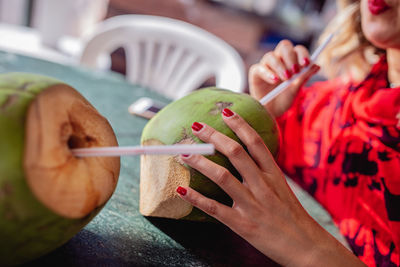 Close-up of young woman holding coconut water at table