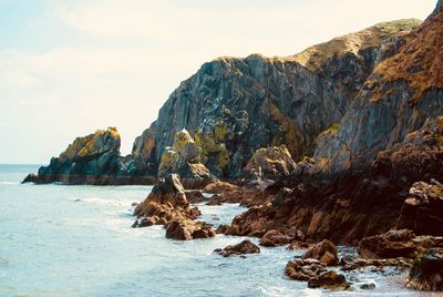 Rock formation in sea against sky