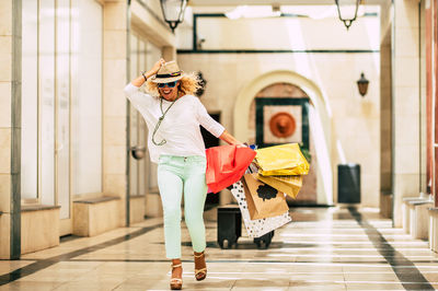 Full length of woman holding shopping bags walking on corridor