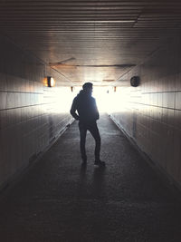 Rear view of silhouette man walking in tunnel