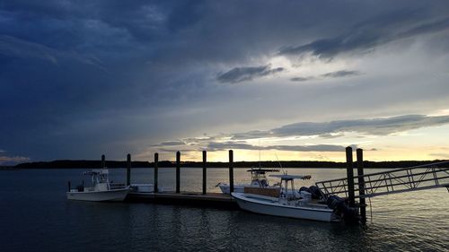 Boats moored in sea against cloudy sky