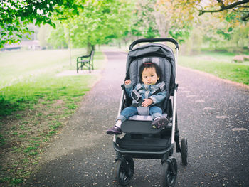 Portrait of baby girl in stroller on road at park