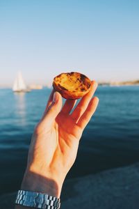 Close-up of hand holding ice cream against sea