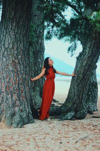 Woman standing by tree trunk