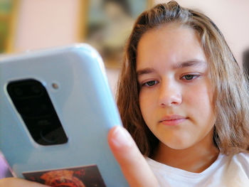 A beautiful girl holds a mobile phone in her hand and looks thoughtfully at the screen.