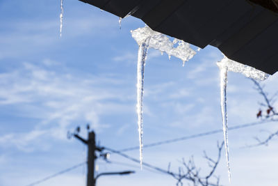 Icicles on the roof, blue sky and iced water, winter ice