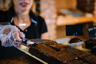 Close-up of young woman preparing brownies at bakery