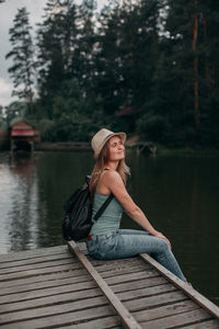 Young girl in a blue top on vacation in a hike with a backpack by the lake in the forest area