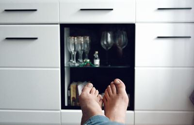 Low section of woman against shelves at home