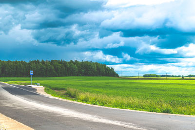 Road by field against sky