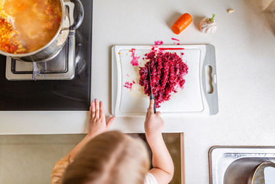 Girl chopping red cabbage on cutting board in kitchen