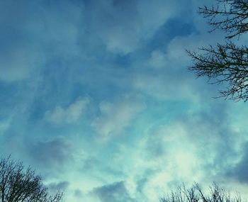 Low angle view of bare tree against cloudy sky