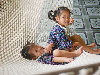 Happy asian baby girls, sisters, enjoys being together on a hammock - sibling relationship