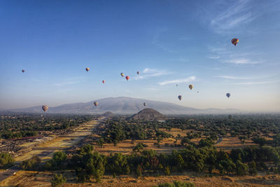 Hot air balloons flying over landscape against sky