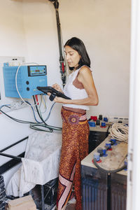 Woman using tablet pc by inverter at solar power station