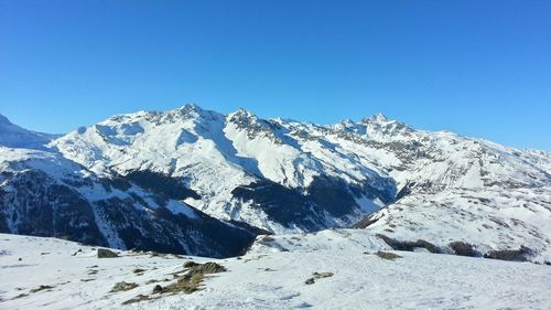 Scenic view of snow covered mountains against clear blue sky