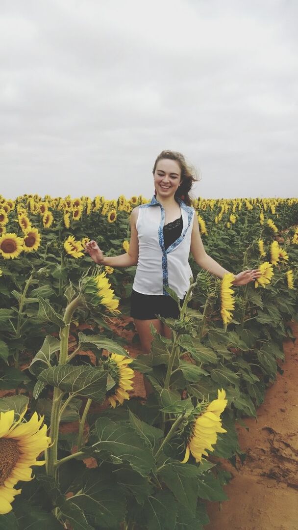 flower, growth, lifestyles, casual clothing, field, freshness, plant, leisure activity, agriculture, sky, person, beauty in nature, nature, young adult, standing, yellow, rural scene, young women