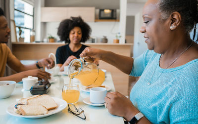 Side view of mature woman drinking tea sitting at home with family