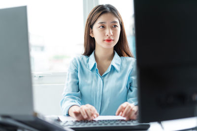 Portrait of young woman using mobile phone in office