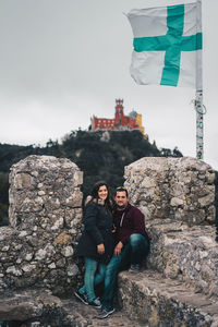 Man and woman standing by historic building against sky