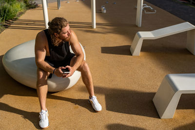 Sportive guy in his twenties doing workout outdoors in the street. using fitness mobile app