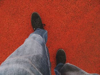 Low section of man standing against red wall