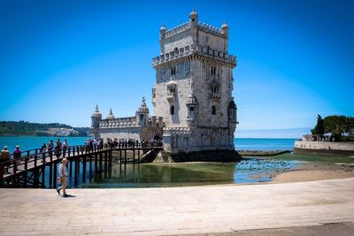 View of building by sea against clear blue sky