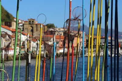 Close-up of multi colored fishing nets against harbour with blue sky.