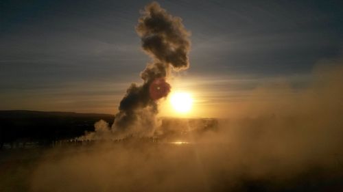 Scenic view of strokkur geyser against sky at sunset