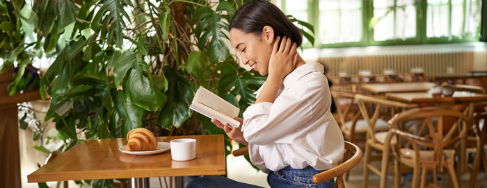 Side view of young woman using mobile phone while sitting at home