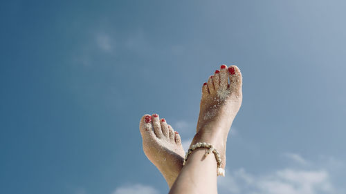 Low angle view of woman feet against sky