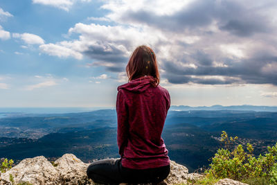 Rear view of woman looking at mountains against sky